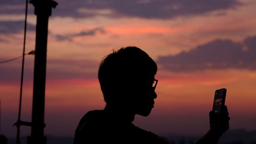 Portrait of silhouette man photographing against sky during sunset
