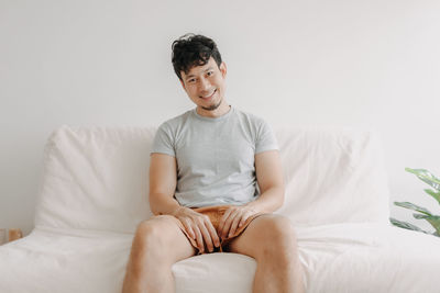 Young woman sitting on bed at home