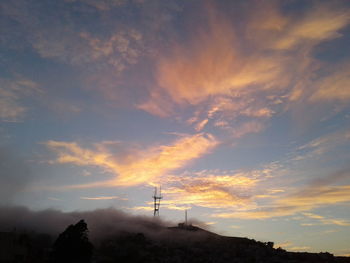 Low angle view of silhouette communications tower against sky during sunset