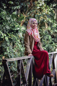 Portrait of young woman standing against trees