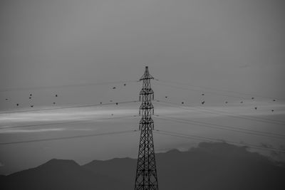 Low angle view of silhouette electricity pylon against clear sky