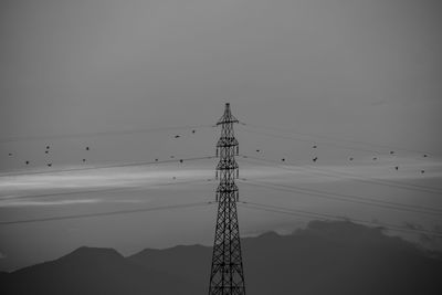 Low angle view of silhouette electricity pylon against clear sky