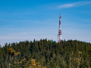Low angle view of communications tower in forest against sky