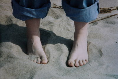 Low section of person standing on sandy beach