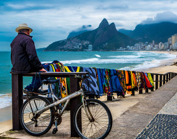 Rear view of man on bicycle by sea against sky