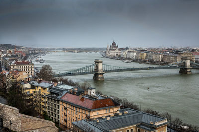 High angle view of buildings by river against sky in city