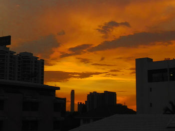 Silhouette buildings against dramatic sky during sunset