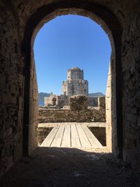 Old buildings against clear blue sky seen through arch window