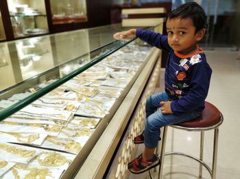 Portrait of cute boy siting on seat at jewelry store