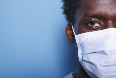 Close-up of man wearing mask against blue background