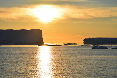 Scenic view of sea against sky during sunset with beautiful icebergs in the midnight sun  greenland