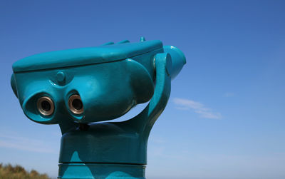 Close-up of coin-operated binoculars against blue sky