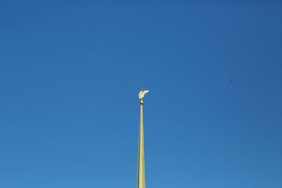 Low angle view of wind turbine against clear blue sky