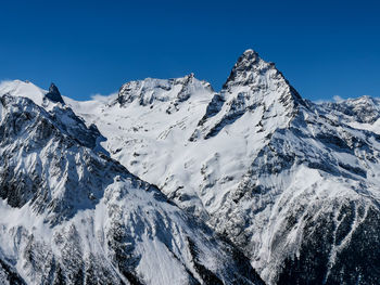 Scenic view of snowcapped mountains against clear blue sky