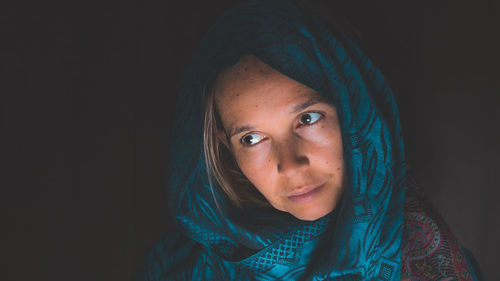 Portrait of young woman against black background