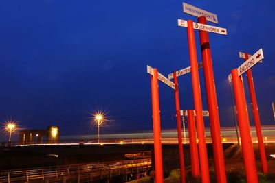 Illuminated information sign against sky at night