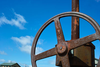 Close-up of rusty machine against blue sky