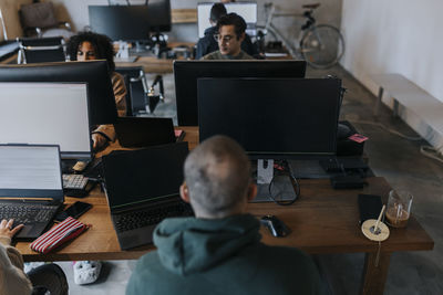 Multiracial male and female computer programmers working at desk in startup company