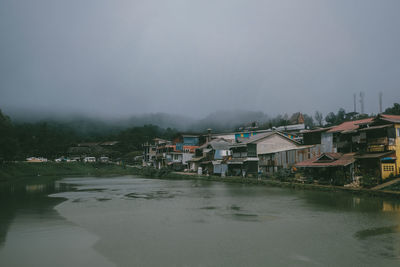 River amidst houses and buildings against sky