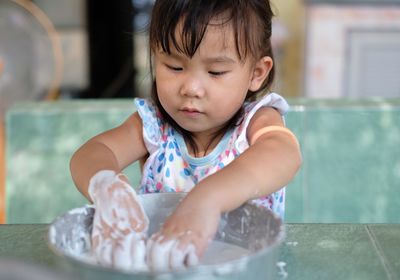 Girl preparing dough at table