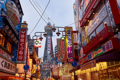 Low angle view of illuminated communications tower in city