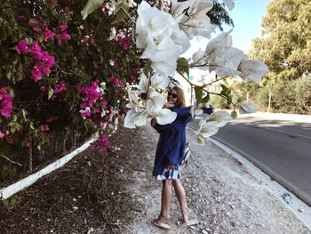 Full length of woman standing by flowering plants