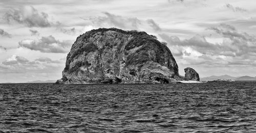 Rock formation in sea against sky