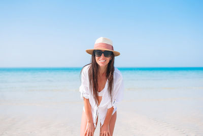 Young woman wearing hat on beach against clear sky