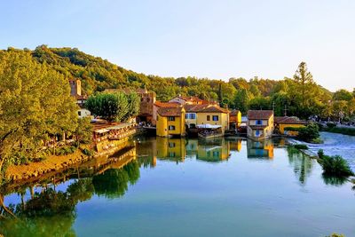 Houses by lake and buildings against clear sky