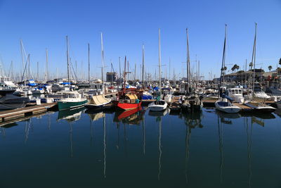 Sailboats moored in calm sea against clear blue sky