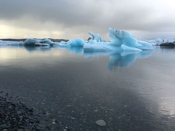 Iceberg in sea against cloudy sky at glacier lagoon