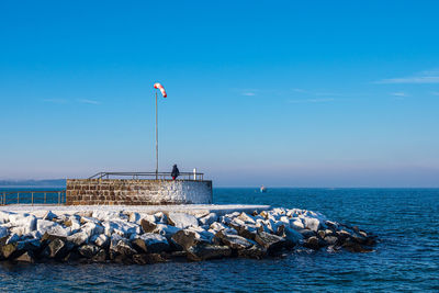 Rear view of person standing by sea against sky