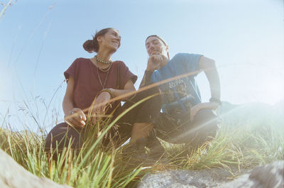 People sitting on field against sky