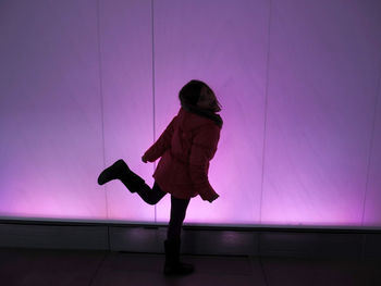 Portrait of girl dancing against illuminated wall