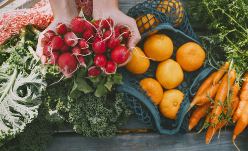 Hands of woman showing fresh radish above table