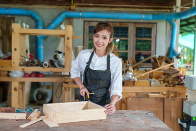 Tutor with female carpentry student in workshop studying for apprenticeship at college ,