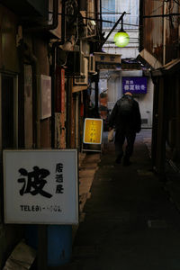 Rear view of man walking on illuminated sign