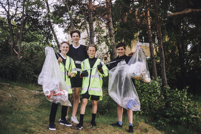 Full length portrait of smiling boys standing with plastic bags