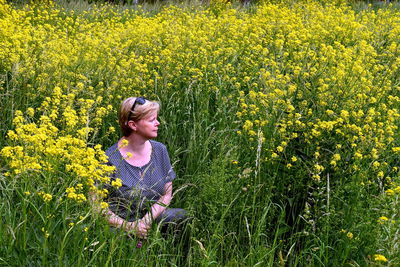 Young woman sitting on yellow flower in field