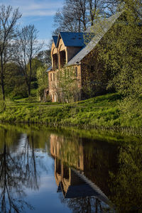 Scenic view of lake by trees and buildings against sky