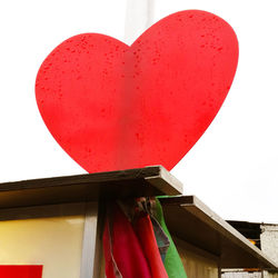 Low angle view of heart shape hanging on building against sky