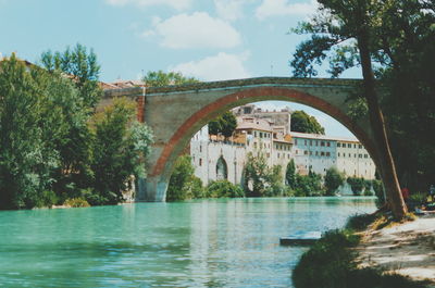 Arch bridge over river against sky