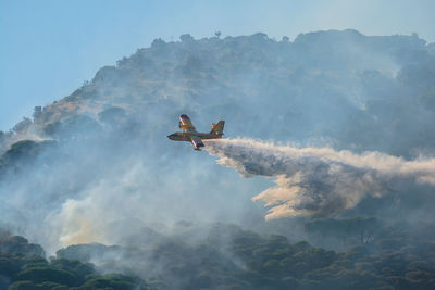 Airplane flying over mountain against sky