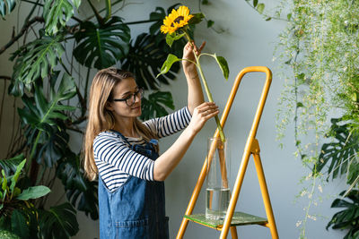 Young woman smiling while standing against plants