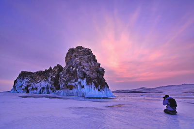 Man photographing rock formation during winter