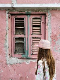 Low angle view of girl standing against closed window