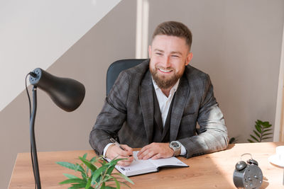 Businessman writing notes while sitting at his desk. young bearded man