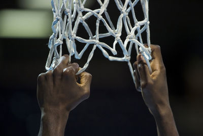 Cropped hands of man holding basketball hoop in court