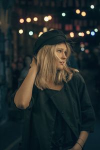Portrait of beautiful woman standing in city at night