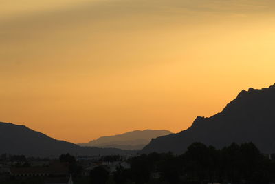 Scenic view of silhouette mountains against romantic sky at sunset